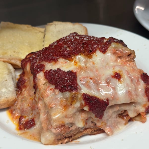 Cheesy lasagna with red sauce and melted mozzarella, served alongside garlic bread.